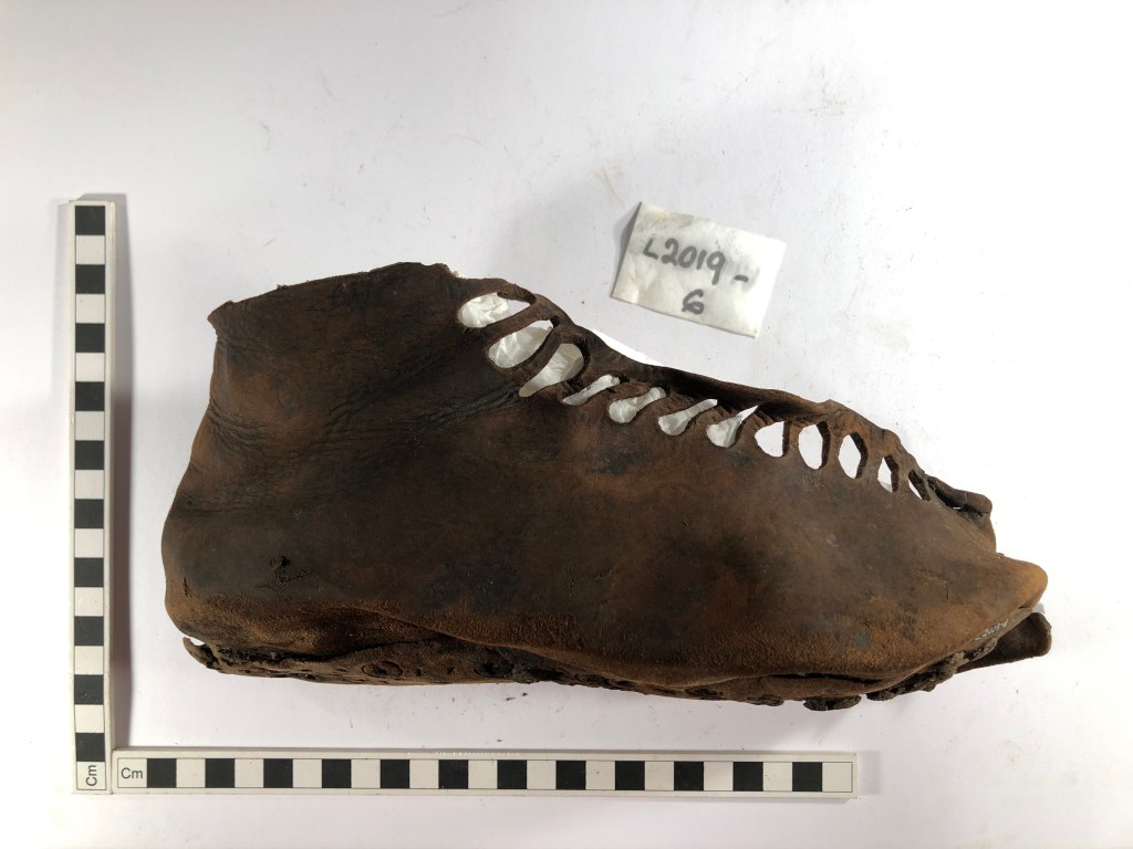 Image depicts a brown leather military boot with holes for laces up the top of the boot. 