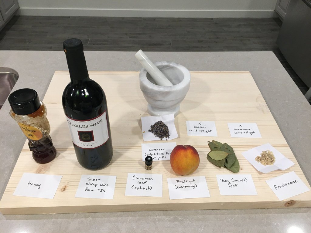A collection of modern items used to make incense displayed on a table. These include wine, honey, lavender, bay leaves and frankincense. 