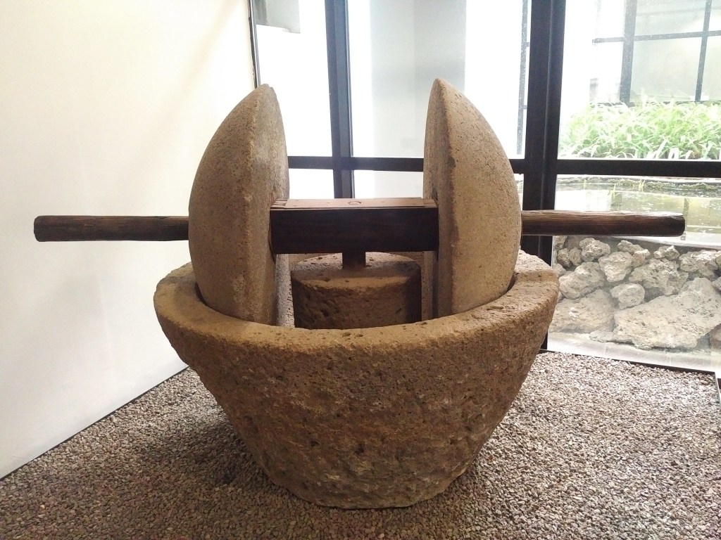 A trapetum (or olive press) which is circular in shape with two vertical hemispherical stone objects inside and a wooden plank through their centre to move the press. 