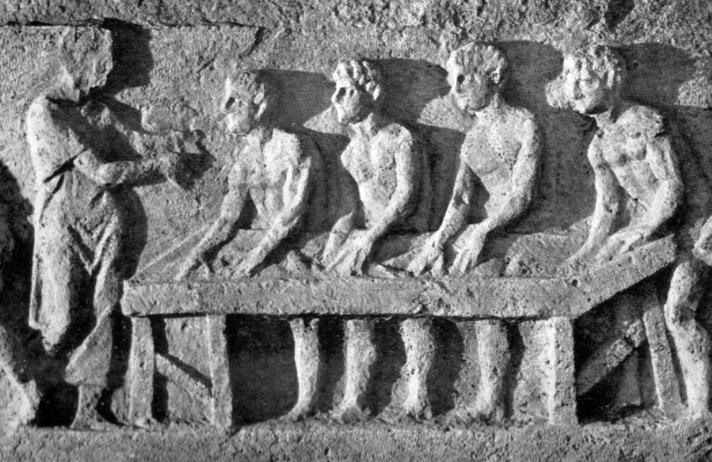 Relief from the Tomb of Eurysaces in Rome depicting 4 men shaping loaves of bread, while another man oversees their work to the left of the scene. 
