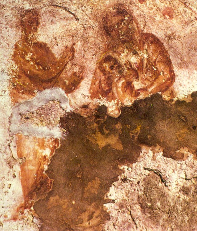 Image of a partially destroyed painting of a seated mother and child with a male figure standing to their proper right pointing upwards. 