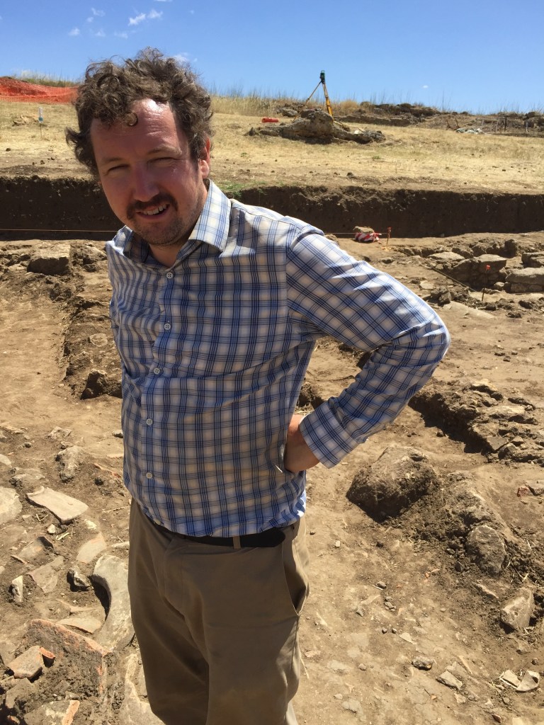 Dr. Jared Benton standing in the middle of an excavation trench.
