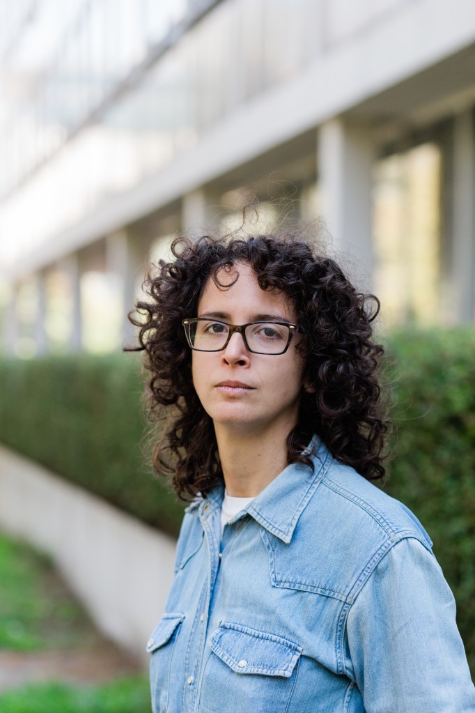 Headshot out Kate Minniti outside of a building on the campus of the University of British Columbia. 