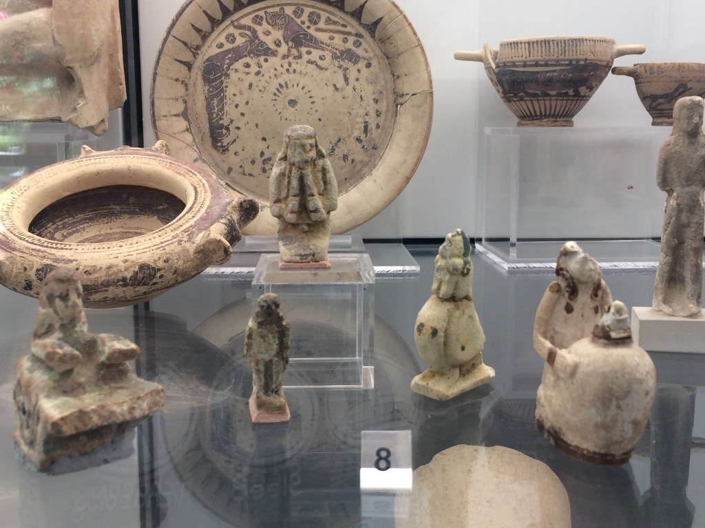 Faience figurines in a display case in the Museo Archeologico Regionale, Palermo. Here we have a flute player, rooster, and falcon, amongst other objects.