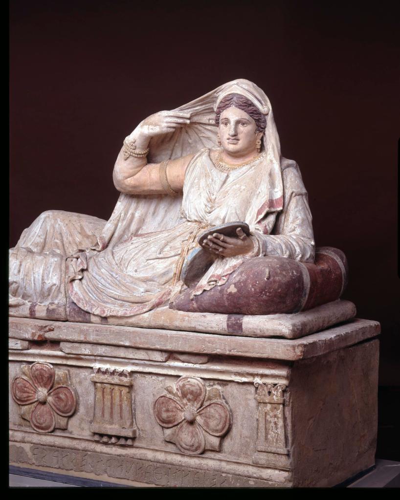 Seianti holds a large lidded bronze mirror in her left hand, on which she wears six rings