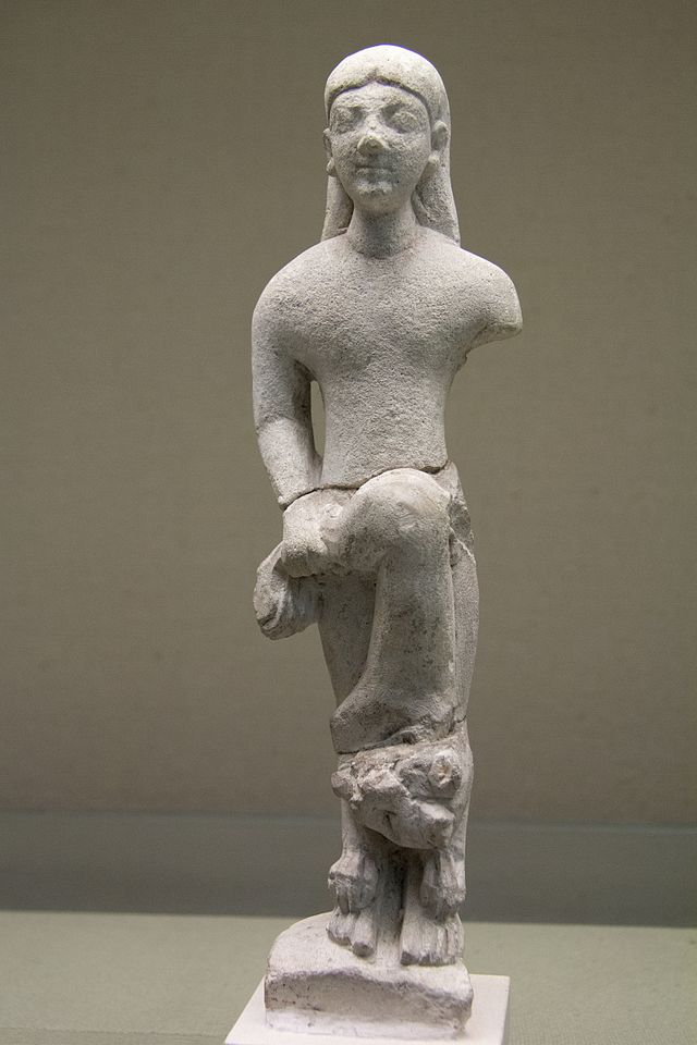 Image of limestone figurine - human with long hair holding a lion upside down at waist with right hand; left arm missing