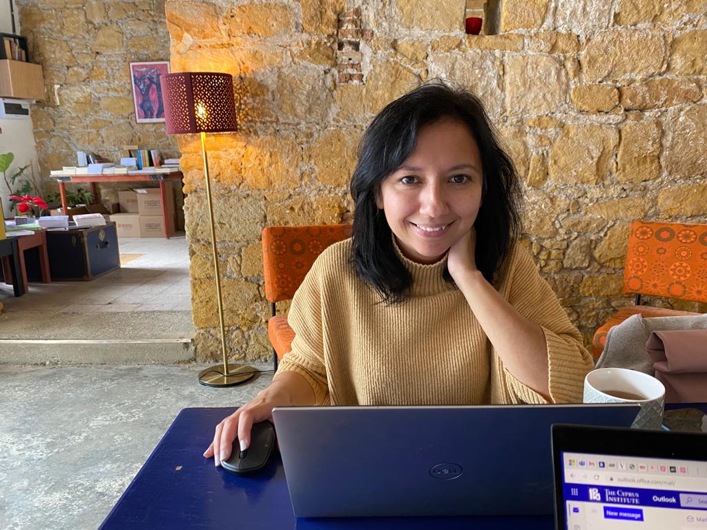 Dr. Nikita sitting at a blue desk infant of a laptop computer.