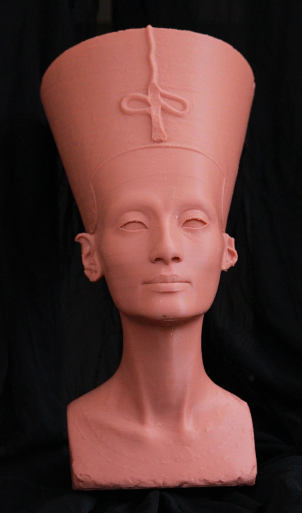 A red-coloured 3D-printed bust of the Egyptian goddess Nefertiti, who wears a large crown on top of her head. 