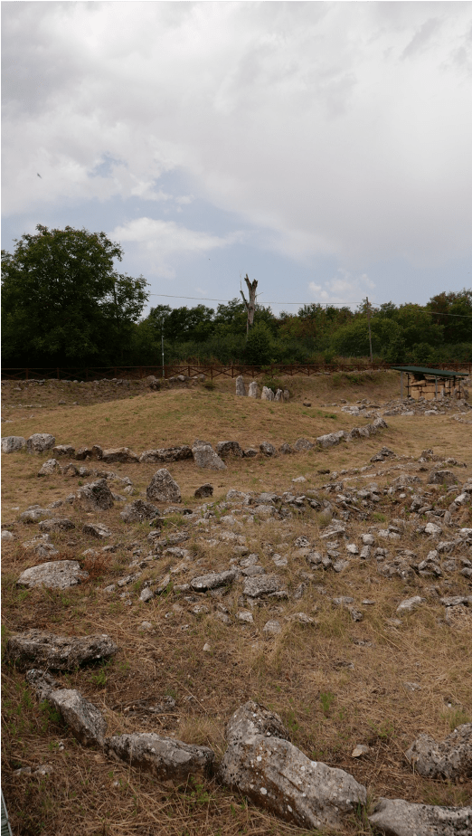 A series roughly hewed stones around a small, raised circle feature in the landscape.