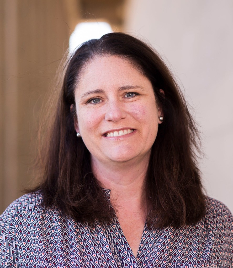 Headshot of a white woman with medium-length straight brown hair.