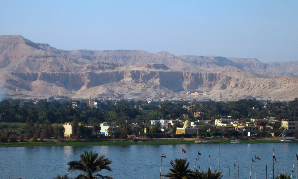 Image of the cliffs of Thebes with the Nile in the foreground.