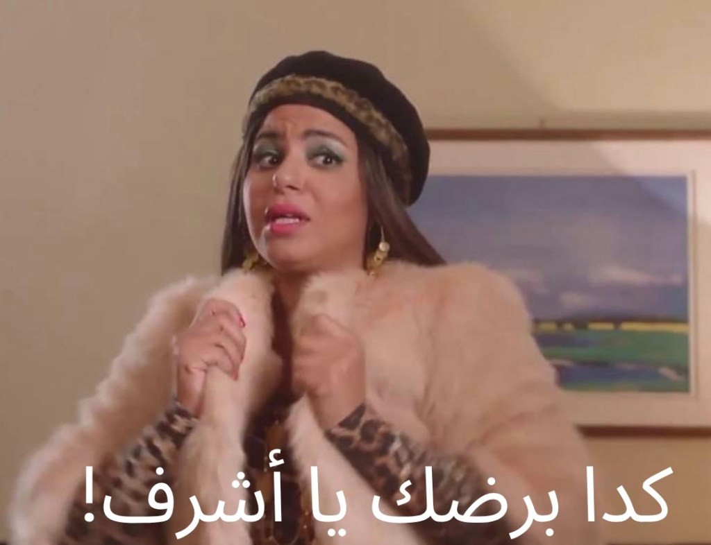 An Egyptian meme with arabic text. A woman wearing a hat holds the collar of her fur coat with both hands, while looking skeptically off to the side.