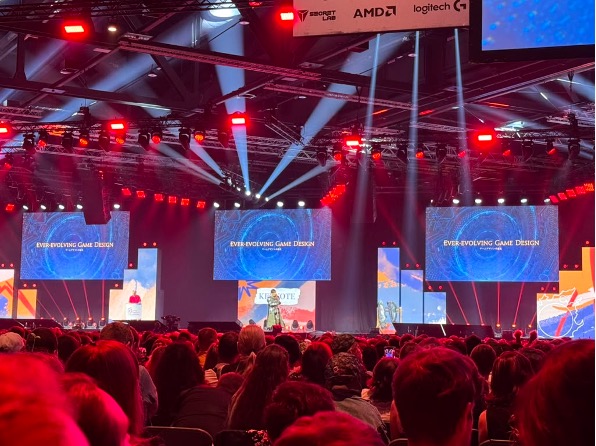 Photo of a man standing on stage in front of three large screens.